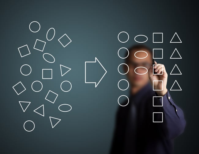 Man on clear board organizing shapes into groups and labeling them based on features of interest. Analogous to the categorization of NLP data.