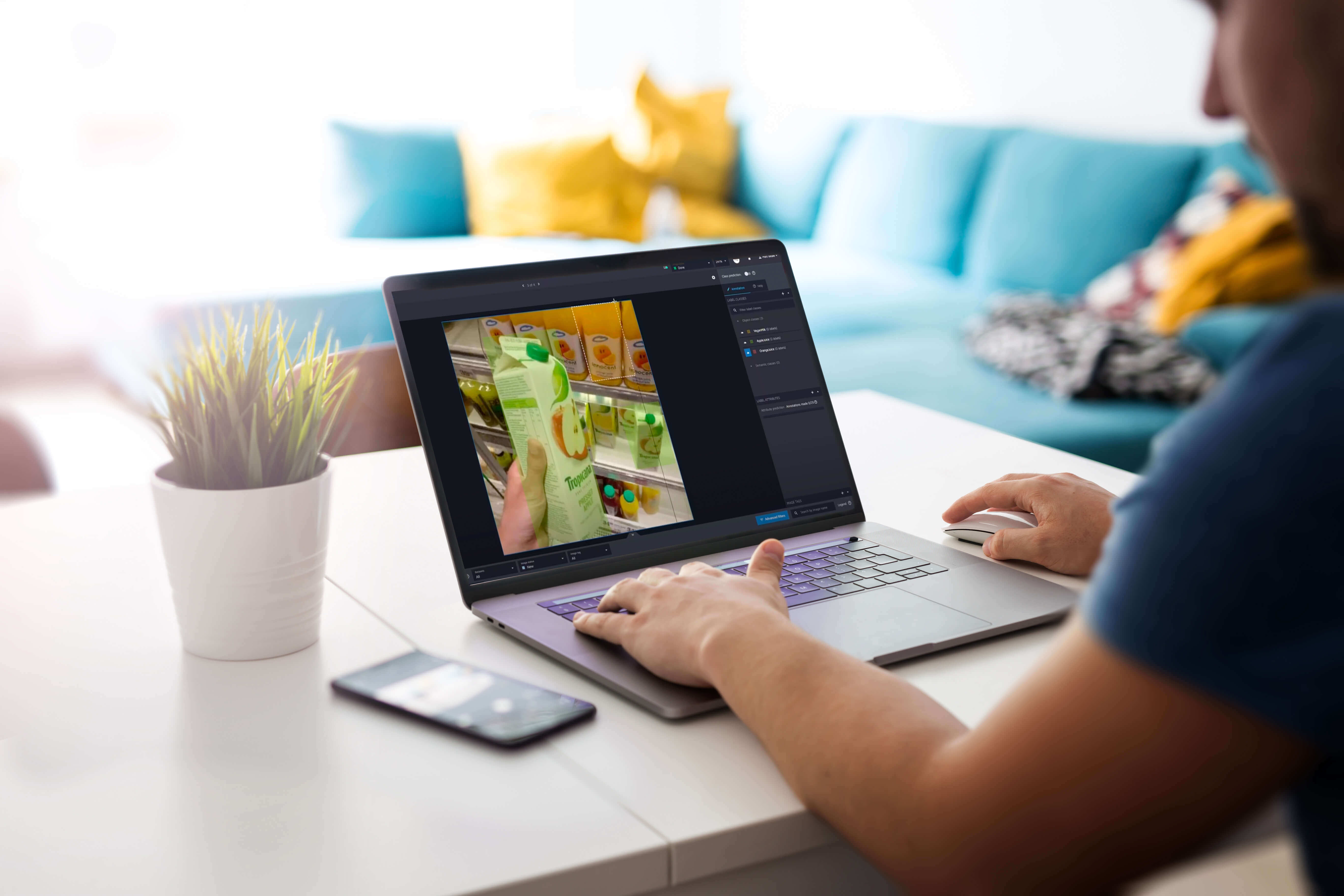 A person viewing a laptop screen; on the screen is a hand grabbing a quart of Tropicana orange juice from the store shelf.